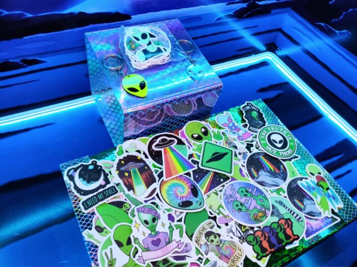 Paquete de 50 stickers y 2 llaveros Alien de Mundo Alien, con diseños únicos y resistentes al agua, ideales para los aficionados a la cultura extraterrestre.